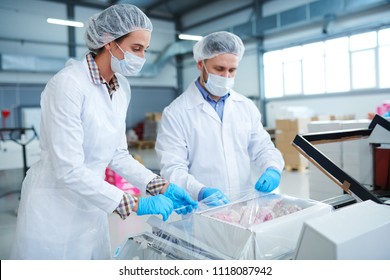Confectionery factory employees in white coats packing paper box with pastry into plastic film. - Shutterstock ID 1118087942