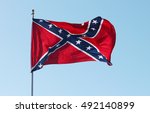 Confederate rebel flag waving in the wind against the blue sky background in Charleston, South Carolina, USA.