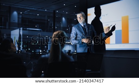 Conference Business Meeting Presentation: Chief Executive Officer Shows Data to Diverse Group of Investors, Businessspeople. Projector Screen Shows Graphs, Product Sales Growth, e-Commerce Analysis