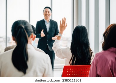 In a conference, business professionals raise their hands to ask questions, vote, or volunteer, highlighting teamwork and active audience involvement in a corporate setting. - Powered by Shutterstock