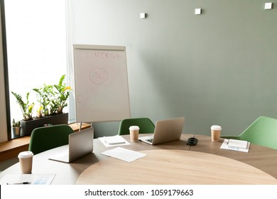 Conference Table With Laptops And Chairs In Empty Meeting Room With Nobody, Modern Company Office Boardroom Interior With Flip Chart For Daily Work And Corporate Team Group Business Briefings Concept