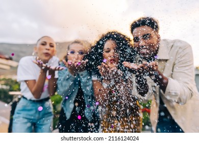 Confetti celebrations on the rooftop. Group of vibrant friends blowing colourful confetti during a party outdoors. Multicultural friends having fun together on the weekend. - Powered by Shutterstock