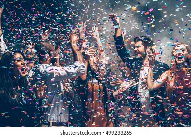 Confetti Fun. Group Of Beautiful Young People Throwing Colorful Confetti While Dancing And Looking Happy