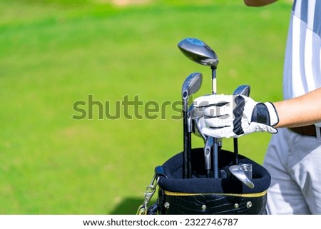 Confidence Asian man golfer choosing golf club in golf bag for golfing on golf course fairway. Healthy people enjoy outdoor activity lifestyle sport training at country club on summer holiday vacation