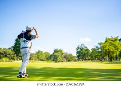 Confidence Asian man golfer holding golf club hitting golf ball on the green at golf course in sunny day. Healthy male enjoy outdoor lifestyle activity sport golfing at country club on summer vacation - Powered by Shutterstock