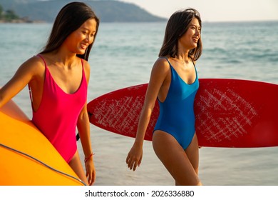 Confidence Asian woman girl friends in swimwear holding surfboard and walking together on the beach at summer sunset. Female friendship enjoy outdoor activity lifestyle play extreme sports surfing - Powered by Shutterstock