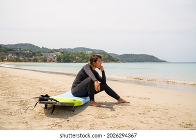 Confidence Asian Woman In Wetsuit Holding Surfboard And Walking On Tropical Beach At Summer Sunny Day. Healthy Sportswoman Enjoy Outdoor Active Lifestyle Play Extreme Sport Surfing On Summer Vacation