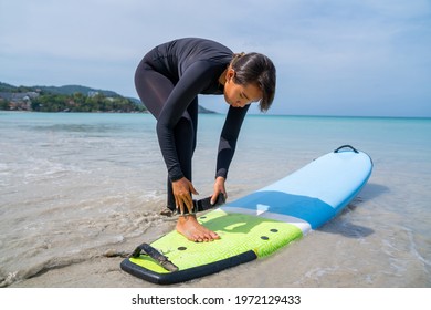 Confidence Asian Woman In Wetsuit Wear Surfboard Safety Leg Rope Before Surfing On Tropical Beach. Healthy Sportswoman Enjoy Outdoor Active Lifestyle Play Extreme Sport Surfing On Summer Vacation.