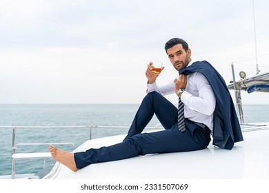 Confidence businessman relax and enjoy luxury outdoor lifestyle drinking whiskey celebrating success business with travel on luxury private catamaran boat yacht sailing in the ocean on summer vacation - Powered by Shutterstock