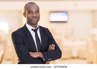 Confidence and charisma. Cheerful young African man in full suit keeping arms crossed and looking at camera - Powered by Shutterstock