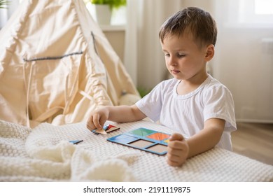 Confidence Male Kid In Pajamas Assembling Geometric Form Shape On Wooden Board Cells At Fabric Wigwam Childish Room. Cute Baby Boy Playing Eco Material Early Development Logic Elementary Education