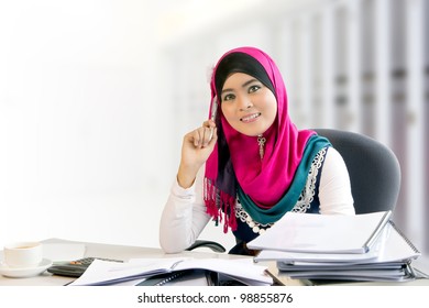 Confidence and smiles of young busy muslim businesswoman while working