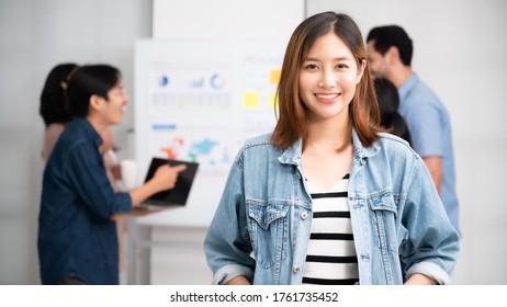 Confidence Team Leader. Young Women Asian Owner Startup Business Looking Camera With Smile While His Colleagues Working In The Background