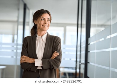 Confident 45 years old woman business owner standing in office. Middle aged businesswoman manager, mature female professional executive, corporate leader wearing suit looking away thinking of success. - Powered by Shutterstock