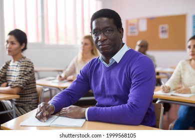 Confident Adult African American Man Wearing Glasses Listening To Lecture In Classroom With Group. Postgraduate Education Concept
