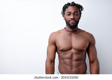 Confident African American Bodybuilder Man With Naked Muscular Torso,Isolated On White Studio Background. Attractive Young Strong Shirtless Guy Having Perfect Body Looking Posing At Camera Indoors