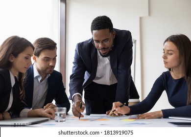 Confident African American businessman hold lead meeting with diverse colleagues in office. Multiracial businesspeople brainstorm discuss company financial paperwork at briefing. Teamwork concept. - Powered by Shutterstock