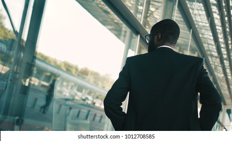 Confident African American Businessman Walking Along Big Office Windows Outdoors. Modern Building. Back View. Shot From Back. Close Up