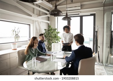 Confident African American businesswoman leading briefing, explaining strategy, training diverse staff sitting at table in boardroom, group negotiations, business partners sharing startup ideas - Powered by Shutterstock