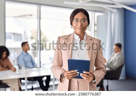 Confident African American businesswoman manager standing at office team business meeting. Portrait of elegant smiling professional woman company executive leader holding digital pad in boardroom.