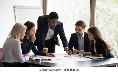 Confident African American Male Boss Work Cooperate With Diverse Team At Office Briefing, Focused Biracial Businessman Head Meeting, Collaborate Discuss Business Ideas With Colleagues At Meeting