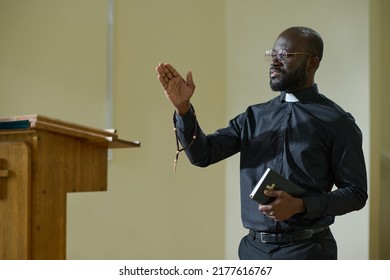 Confident African American man in pastor apparel with clerical collar preaching during church service in front of parishioners - Shutterstock ID 2177616767