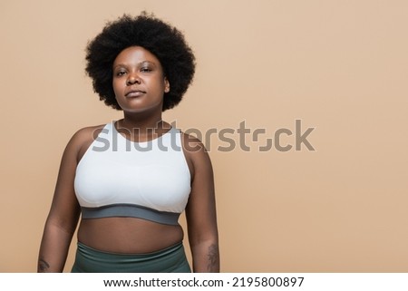 confident african american plus size woman in crop top isolated on beige