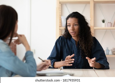 Confident African American woman candidate speaking at job interview, answering hr manager employer questions, diverse business partners colleagues discussing project strategy, sharing ideas
