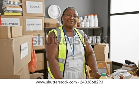 Confident african american woman volunteer, smiling and standing proud at charity center. working in unity, she personifies altruism in her reflective vest.