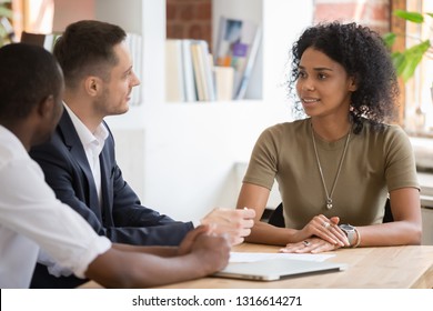Confident african black female applicant talking to diverse hr managers recruiters at job interview, recruiting team listening to candidate woman making good impression, employment and hiring concept