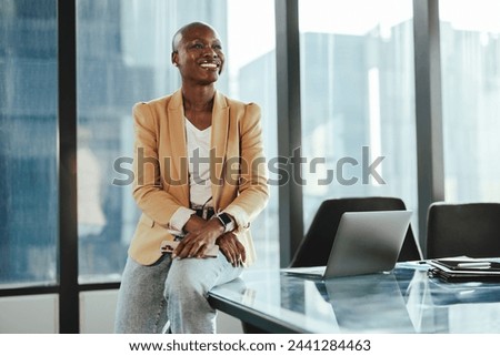 Confident African businesswoman in an office, sitting at a table. She is happy and successful, smiling while looking away