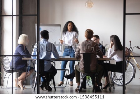 Confident african businesswoman presenter coach give corporate whiteboard presentation training multiracial people group explain project at team briefing staff conference, business education concept