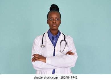 Confident African Female Doctor Wear White Lab Coat, Stethoscope Look At Camera Stand On Mint Green Studio Background. Serious Proud Black Woman Professional Therapist Physician Arms Crossed Portrait.