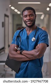 Confident Afro American Nurse Posing In Hospital Hall Aisle, Take A Break During Work, Wearing Blue Uniform, Smiling. Medicine And Health Concept