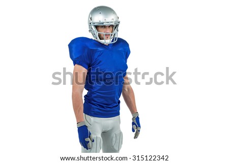 Confident American football player standing against white background