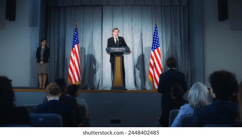 Confident American republican politician delivers successful speech to supporters at government election rally. New president of USA gives interview for media. Backdrop with American flags. Zoom out. - Powered by Shutterstock