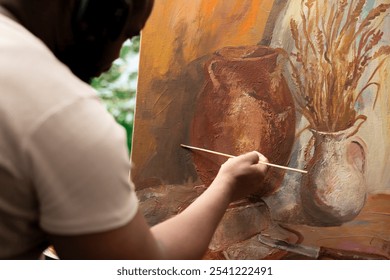 Confident artist stands before a canvas creating a beautiful painting with watercolor paints, fine bristles pattern. Making a colorful and inspired artwork with brush kit and paint tubes. Close up. - Powered by Shutterstock