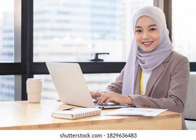 Confident Asia Muslim (Islam) Businesswoman Executive Dressed In The Religious Veil, Working In The Modern Office And Looking At Camera And Smile. Work Concept Of Diversity Of Culture.