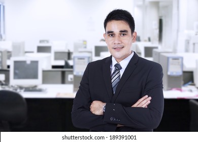 Confident asian businessman with arms crossed at office