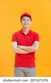 Confident Asian Delivery Man Smiles And Looks At Camera With Crossed Arms.