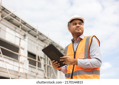 Confident Asian Engineer Man Using Tablet For Checking And Maintenance To Inspection At Modern Home Building Construction. Architect Working With White Safety Helmet In Construction Site