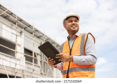 Confident Asian Engineer Man Using Tablet For Checking And Maintenance To Inspection At Modern Home Building Construction. Architect Working With White Safety Helmet In Construction Site