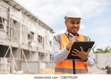 Confident Asian Engineer Man Using Tablet For Checking And Maintenance To Inspection At Modern Home Building Construction. Architect Working With White Safety Helmet In Construction Site