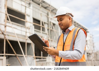 Confident Asian Engineer Man Using Tablet For Checking And Maintenance To Inspection At Modern Home Building Construction. Architect Working With White Safety Helmet In Construction Site