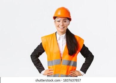 Confident Asian Female Architect, Construction Engineer In Safety Helmet, Protective Glasses Ready To Enter Building Area For Inspection, Smiling Satisfied With Results Of Work, White Background