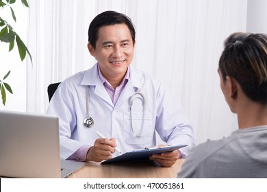 Confident Asian Male Doctor Discussing Diagnosis With Patient In Office