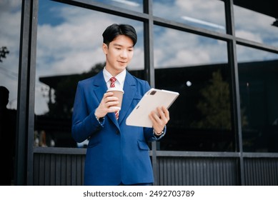 Confident Asian man with a smile standing holding notepad and tablet at out side office. big city on business center background.
 - Powered by Shutterstock