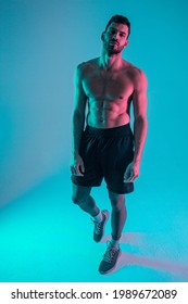 Confident athletic bearded european young man. Front view of guy with naked sportive torso and looking at camera. Isolated on blue background. Studio shoot. Copy space