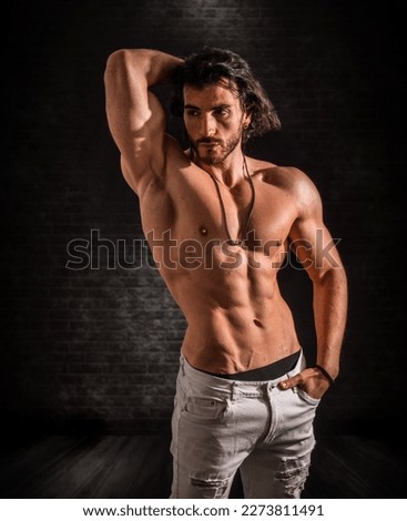 Confident, attractive shirtless muscular young man with open vest on