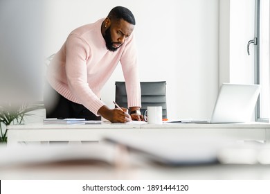 Confident attractive young african businessman working in the office, using laptop computer - Shutterstock ID 1891444120